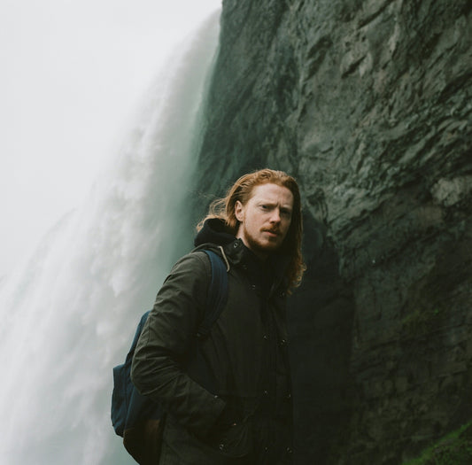 man in black jacket standing beside rock formation