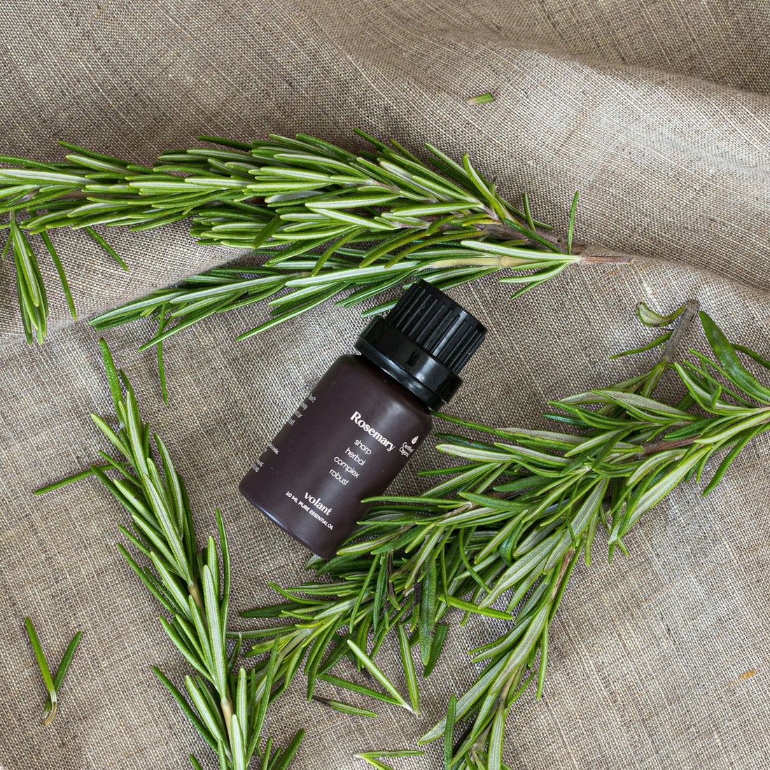 a bottle of rosemary essential oil sitting on top of a cloth